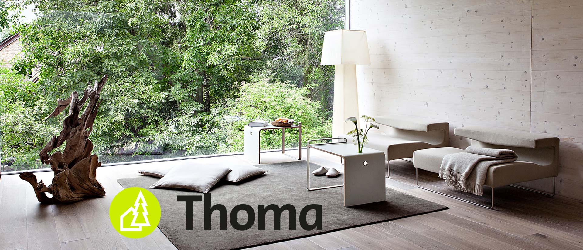 Wohnzimmer mit Blick in einen Garten mit Logo von Thoma