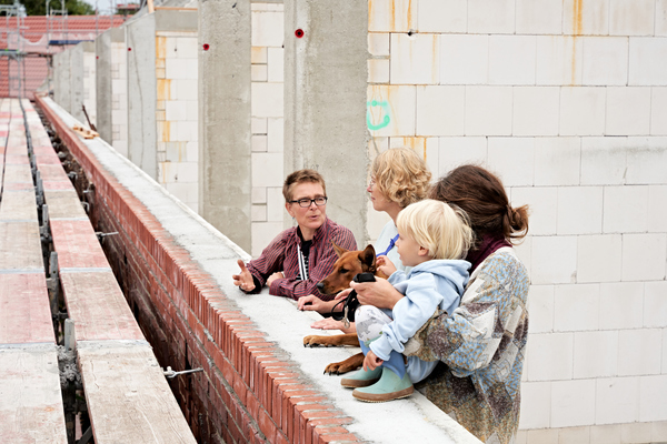 Drei erwachsene Menschen, Kind und Hund auf einer Baustelle