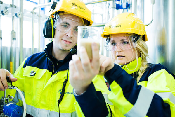 GLS Klimafonds Eine Frau und ein Mann mit Schutzausrüstung und einem Reagenzglas