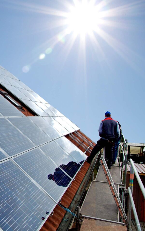 Photovoltaik Dachanlage und ein Handwerker auf einem Gerüst