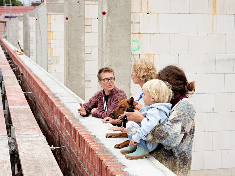 3 Frauen mit einem Kind und Hund in einem Rohbau.