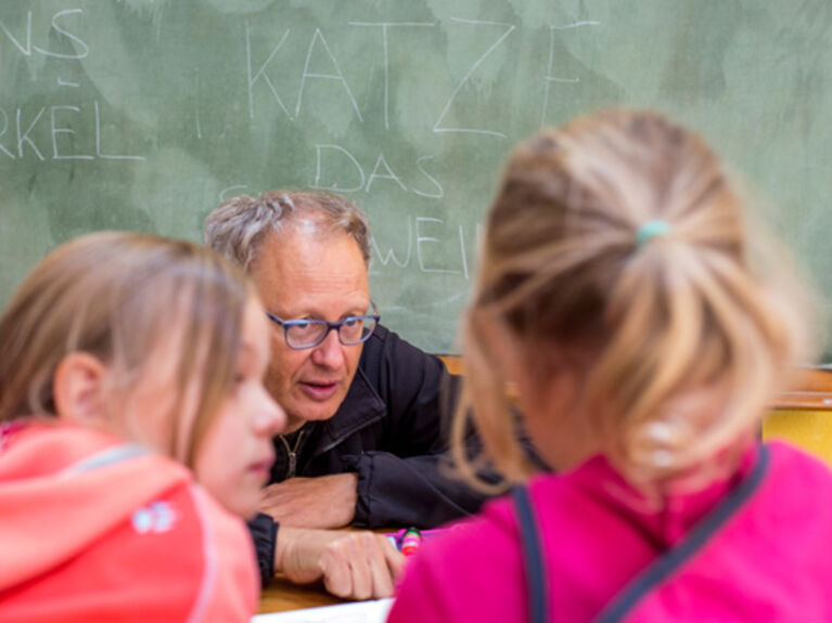 Ein Lehrer unterrichtet zwei Mädchen